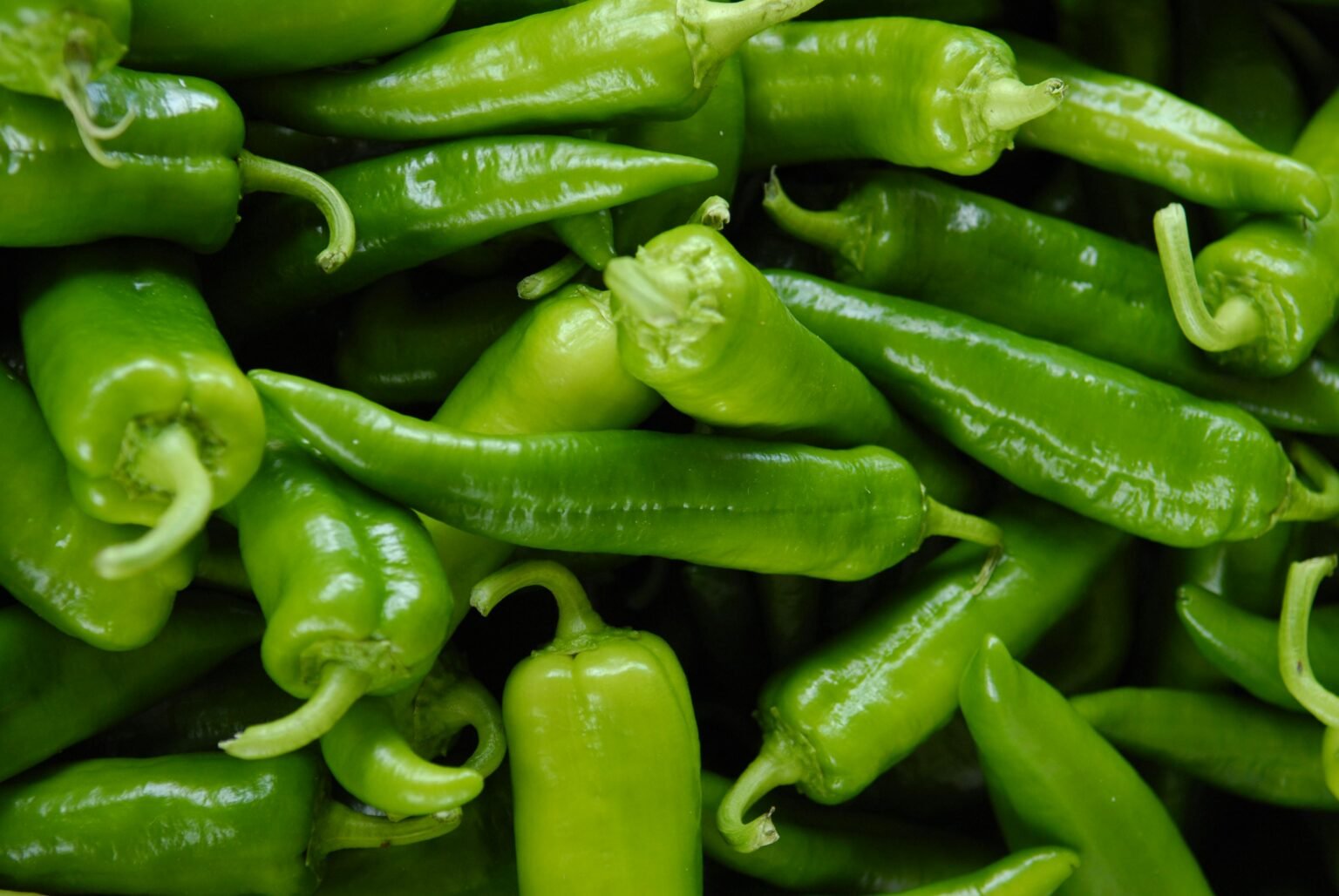 A vibrant close-up of fresh organic green chili peppers showcasing their glossy texture and natural freshness.